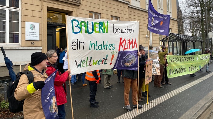 Vor dem Landgericht Detmold protestieren Bauern. Ein Banner zeigt den Schriftzug "Bauern brauchen ein intaktes Klima".