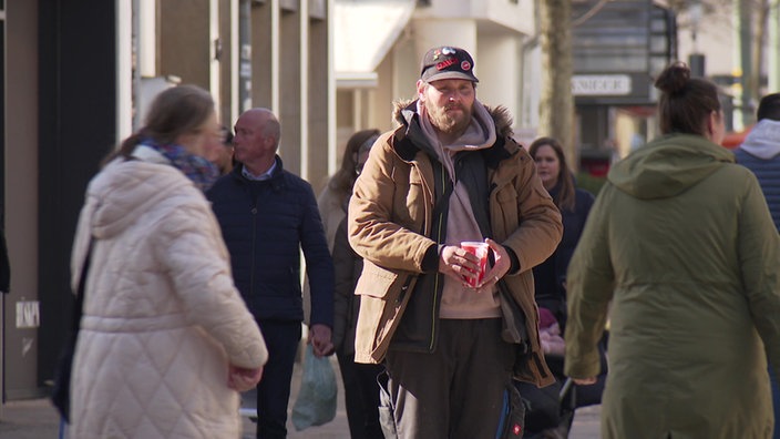 Zwei Männern stehen in der Fußgängerzone und fragen um Geld.