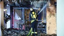 Ein Feuerwehrmann steht in Brandüberresten und löscht weitere Flammen