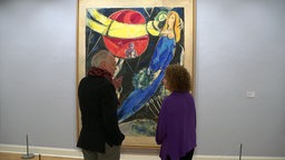 Museumsdirektor Markus Müller unterhält sich mit Meret Meyer vor einem Werk von Chagall.