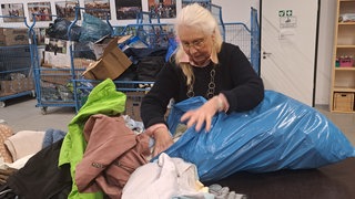 Eine Frau, die einen Blauen Sack mit Spenden durchschaut.