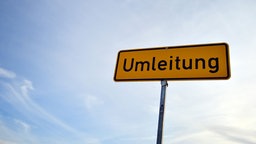 Schild mit der Aufschrift "Umleitung" vor blauem Himmel