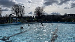 Menschen im Schwimmbecken eines Freibades