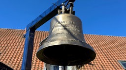 Die Friedensglocke hängt vor blauem Himmel. 