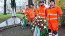 Straßenärter stehen hinter Gedenkkränzen