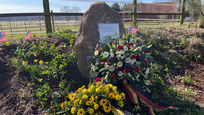 Ein Gedenkstein von Blumen umgeben 