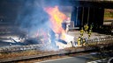 Gefahrguttransporter in Flammen auf der Autobahn wärend Einsatzkräfte den Brand löschen 