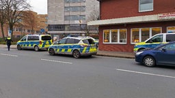 Drei Polizeiwagen vor einem Gebäude. 