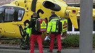 Hubschrauber, mit zwei Rettungsmänner vor dem Einstieg. 