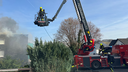 Feuerwehrmänner mit Feuerwehrauto und Drehleiter vor rauchendem Haus