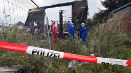 Polizisten zwischen den verbrannten Resten einer Baustelle.