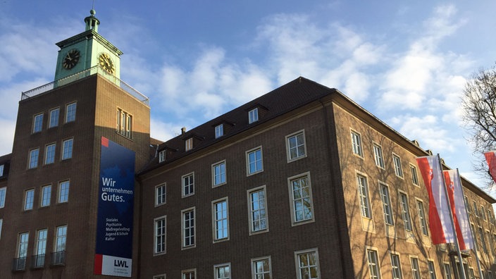 Außenansicht des Landschaftsverbandes Westfalen-Lippe, mit großem Plakat und Fahnen vor dem Gebäude