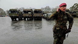 Ein Soldat vor geparkten Militärfahrzeugen.