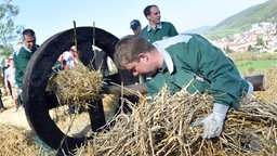 Männer stopfen ein Holzrad mit Stroh