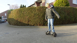 Oskar steht in einem Wohngebiet auf einem Hoverboard.