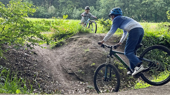 Zwei Jugendliche auf Mountainbikes in hügeligem Gelände