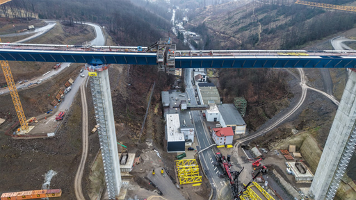 Zwei Brückenpfeiler ragen in die Luft. Darauf liegen zwei blaue Stahlträger. Die Enden berühren sich fast