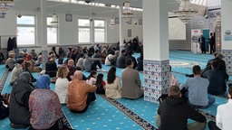 Menschen sitzen im Gebetssaal in der Merkez-Moschee