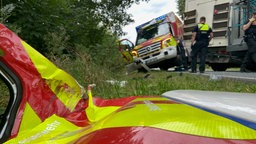 Nach der Kollision mit einem LKW liegt die Tür eines Rettungswagens im Graben neben der Straße