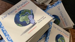 Das Buch "Der kleine Frieden ist dein Begleiter", auf dem Cover ein Hase der eine Weltkugel umarmt