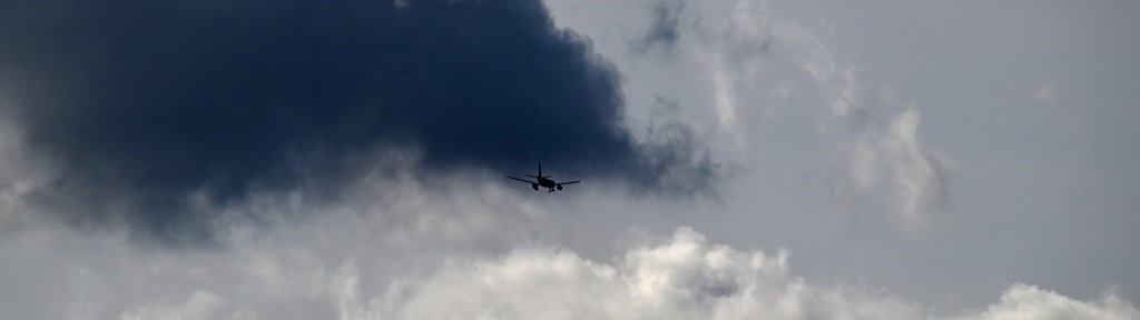 Ein Flugzeug fliegt unter dunklen Wolken