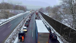 Autos und LKW stehen in Wuppertal nach einem Unfall am Borgholz Tunnel im Stau, an dein Seiten liegt Schnee