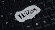 Ein Papierschnipsel mit dem Schriftzug "H@ss" auf einer Computertastatur