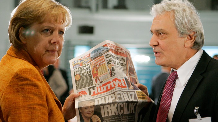 Bundeskanzlerin Angela Merkel, links, und der Journalist Ahmet Kuelahci, rechts, halten die türkische Zeitung „Hurriyet“ vor dem nationalen Integrationsgipfel im Bundeskanzleramt in Berlin, Donnerstag, 12. Juli 2007. 