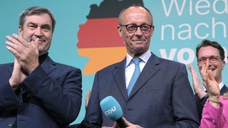 Friedrich Merz (CDU, M), Parteivorsitzender und Kanzlerkandidat, spricht neben Markus Söder (l), im Konrad-Adenauer-Haus nach der Prognose zum Ergebnis der Bundestagswahl.