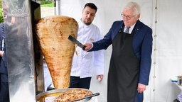 Bundespräsident Frank-Walter Steinmeier (r) schneidet unter Anleitung des Berliner Gastronoms Arif Keles bei einem Empfang des Bundespräsidenten im Garten der historischen Sommerresidenz des deutschen Botschafters Döner. 