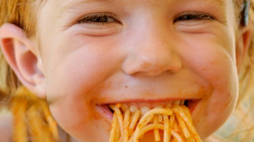 Bambina che mangia spaghetti