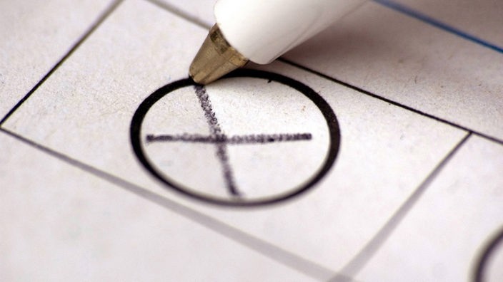 Mit einem Kugelschreiber wird auf einem Stimmzettel ein Kreuz gemacht