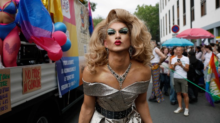 LGBTQ osoba pozira u šljokičavo-srebrnoj haljini 