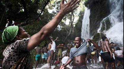 Menschen stehen unter einem Wasserfall