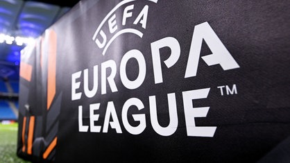 Symbolbild: Banner mit Logo der UEFA Europa League auf Rasen in Stadion (Ausschnitt, Nahaufnahme)