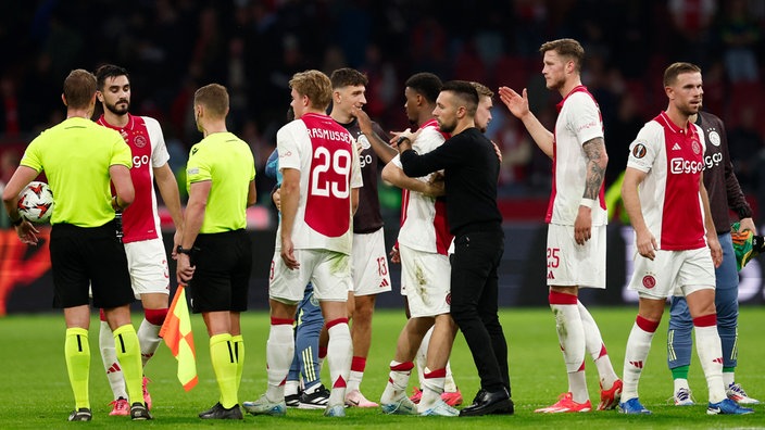 Coach Francesco Farioli (4.v.r.) bespricht sich nach Europa League-Spiel mit dem Team aus Amsterdam auf dem Platz, links im Bild auch zwei Schiedsrichter