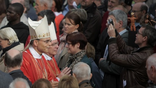 Bischof Franz-Peter Tebartz-van Elst (Mitte vorn) am 15.09.13 inmitten einer Menschenmenge bei der Ankunft zu einem Gottesdienst im Innenhof der Sankt Angela-Schule in Königstein im Taunus