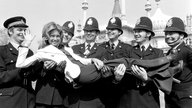 Olivia Newton-John posiert mit Polizisten in Brighton, während der Probe zum ESC 1974