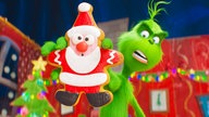 Szene aus dem Animationsfilm "Der Grinch": Ein haariges Monster streckt einen Keks mit Weihnachtsmannmotiv angewidert von sich 