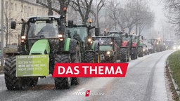 Traktoren fahren bei Schneefall bei einer Demonstration von Bauern über eine Straße. 