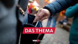 Taschendiebstahl auf dem Weihnachtsmarkt: Eine Hand zieht ein Smartphone aus einer Handtasche