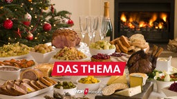 Ein festlich gedeckter Tisch in einem Wohnzimmer mit Kamin und Weihnachtsbaum im Hintergrund