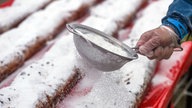 Rerkordstollen auf dem Theaterplatz in Dresden: Ein Helfer bestäubt den Stollen mit Puderzucker (26.11.2022)