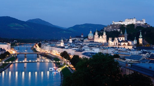 Blick vom Mönchsberg auf die Altstadt von Salzburg mit der Festung Hohensalzburg bei Abenddämmerung.