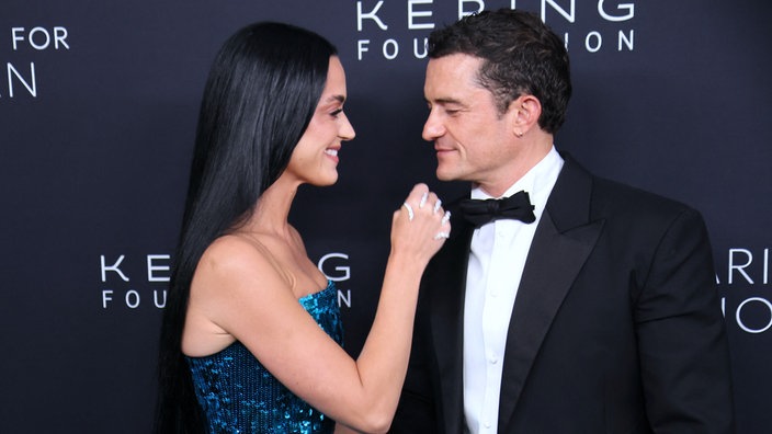 Katy Perry im blauen Abendkleid bewegt ihre Hand zu Orlando Bloom. Beide schauen und lächeln sich am 10.09.2024 an.