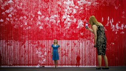 Ein Blick in die Kunstmesse Art Basel wo eine Besucherin ein Bild der Kunstinstallation "The Extended Line" des Künstlers Chiharu Shiota macht.
