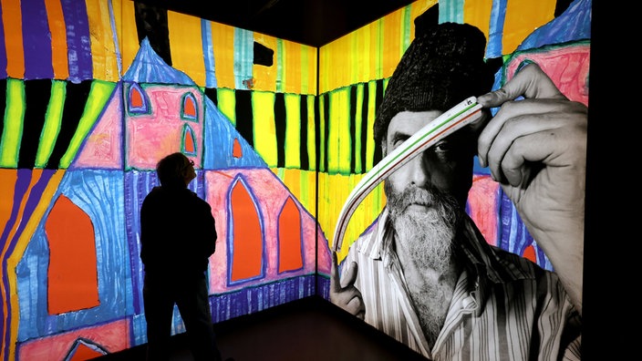 Eine Besucherin steht bei der ersten Ausstellung im neuen Kunstforum Hundertwasser vor einem Portrait des Künstlers.