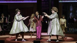 Szenenfoto vom Musical "Hairspray" am Theater Bonn: Menschen in 50er-Jahre-Kleidung singen und tanzen auf der Bühne.