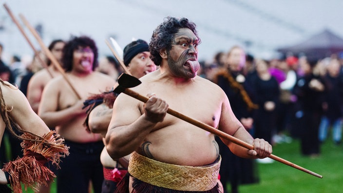 Teilnehmer beim Weltrekord des größten Haka aller Zeiten in Neuseeland: Menschen strecken während des Maori-Rituals die Zunge heraus.