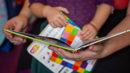 Eine Mutter liest ihrer kleinen Tochter im Kinderzimmer aus einem Buch vor